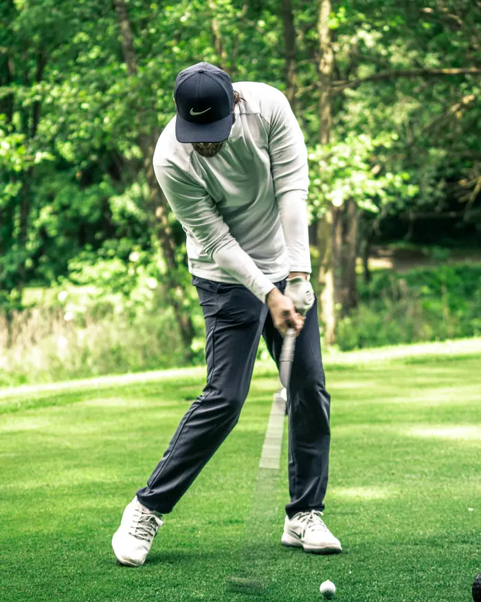 A golfer drives through the ball with a balanced, athletic swing